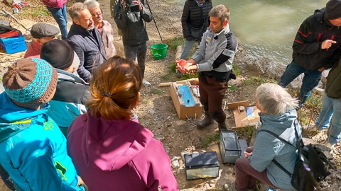 plusieurs personnes en cercle regarde le chabot dans les mains du garde de l'OFB